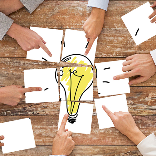 close up of business team with light bulb puzzle